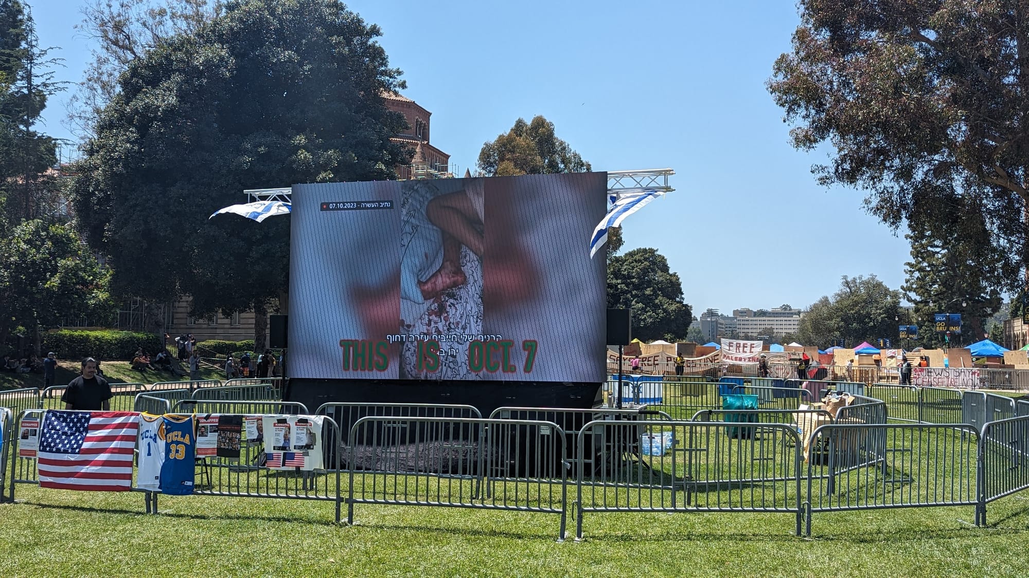 Very large screen showing gruesome images with the text "this is oct 7", surrounded by barriers and nobody around 