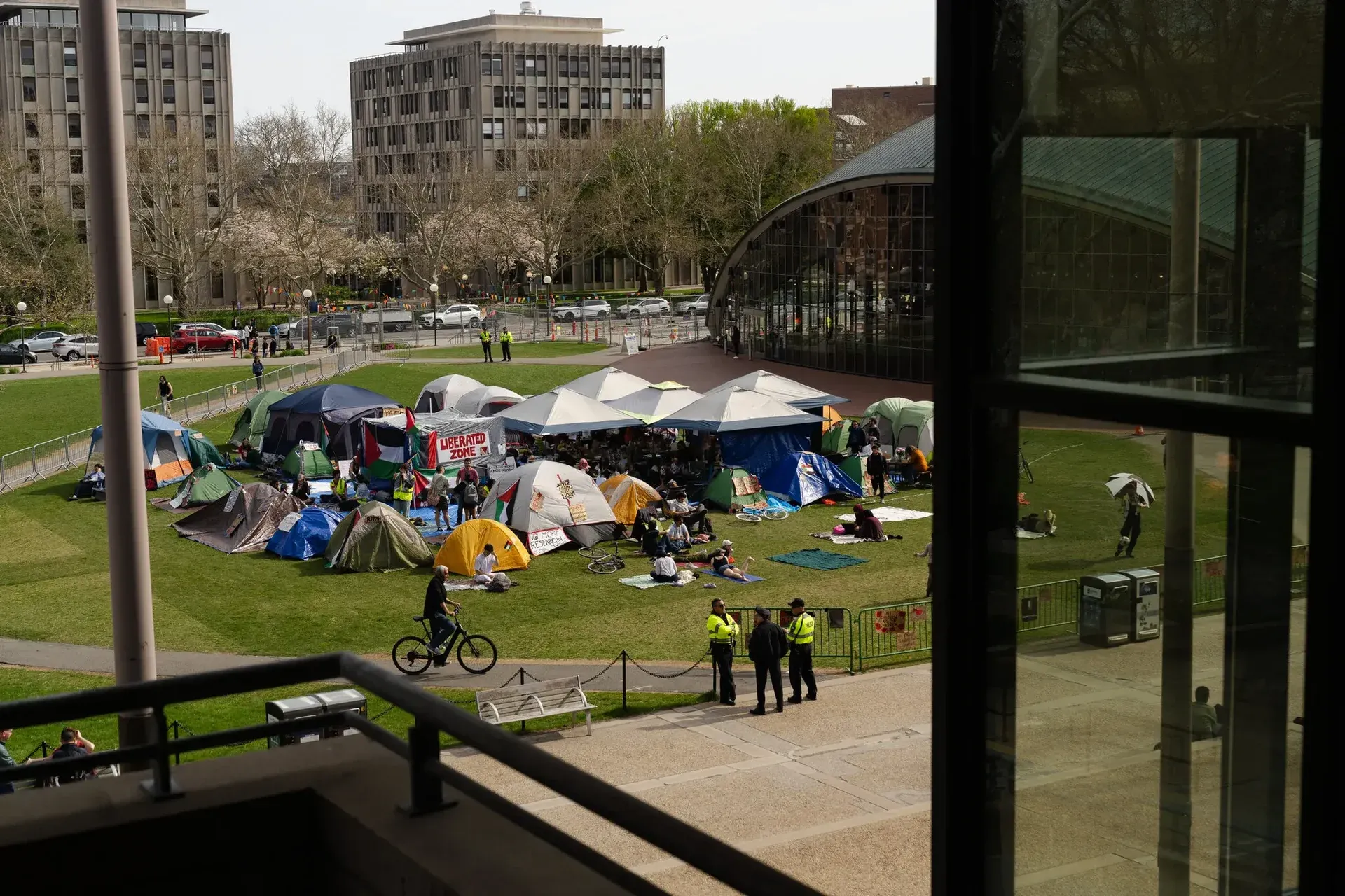 Encampment on a patch of grass in the middle of buildings, like a university campus.