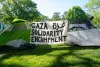 Two tents with a banner in between that reads "Gaza Solidarity Encampment"